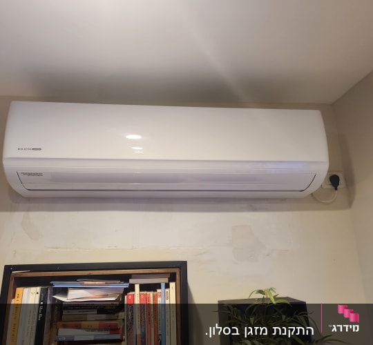 מזגן מותקן על קיר מעל מדף ספרים